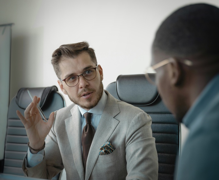 Challenges can arise when asking off work for the Feast, but God is faithful and looks after His people. two men seated in office chairs wearing business suits, with one gesturing with a hand