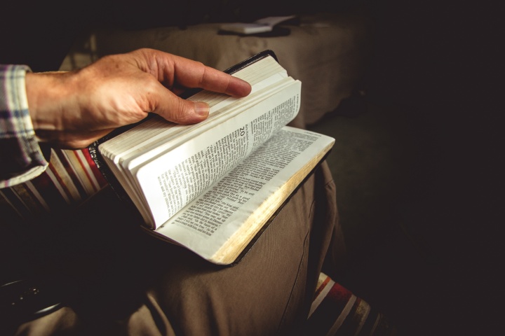 Today those who support the work given to the Church live by faith just as did the patriarchs of old. That is why they have the courage to support this work of God today. They practice tithing because they have faith that God will supply their needs. A person with a Bible on their lap.